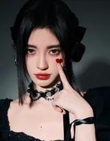 鞠婧祎身着一件设计精良的黑色小礼裙，裙摆微扬，立于光影交织的舞台中央，宛如暗夜中初临人间的精灵，眼神中带着一丝探究与疏离