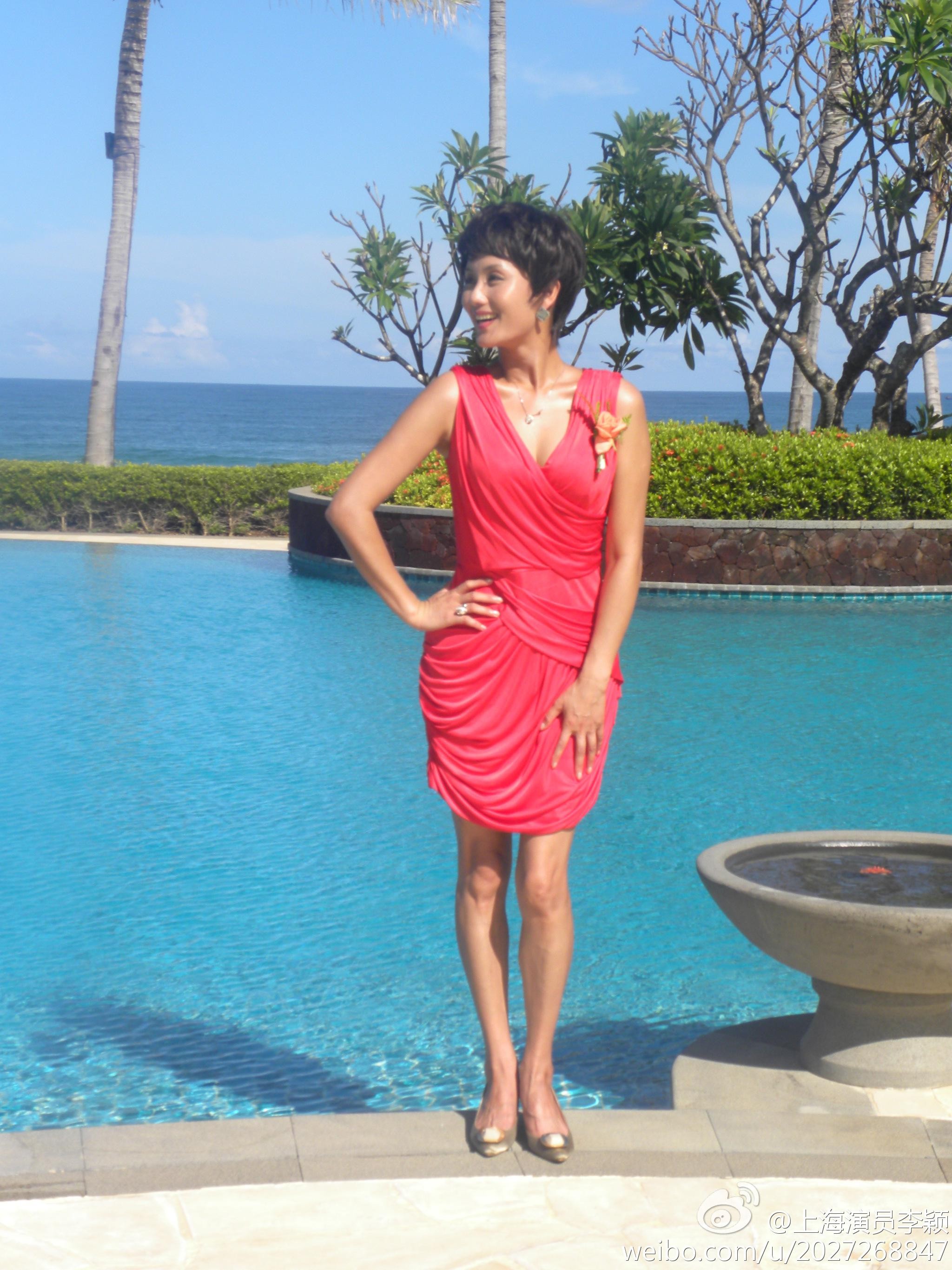 李颖身着红色连衣短裙侧身回眸，眼神充满魅力，完美曲线在灯光下一览无余