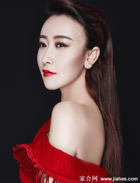 毛俊杰展露明艳笑容，红色背景映衬下肌肤胜雪，活力四射