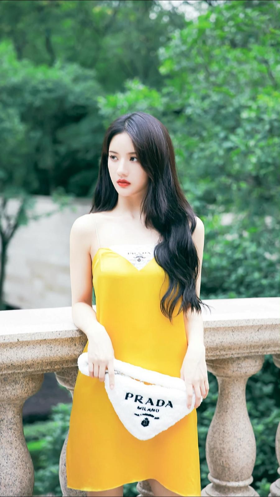 斑驳树影摇曳生姿，她倚着门框望向远方，仿佛沉浸在一个无人打扰的绿色梦境里